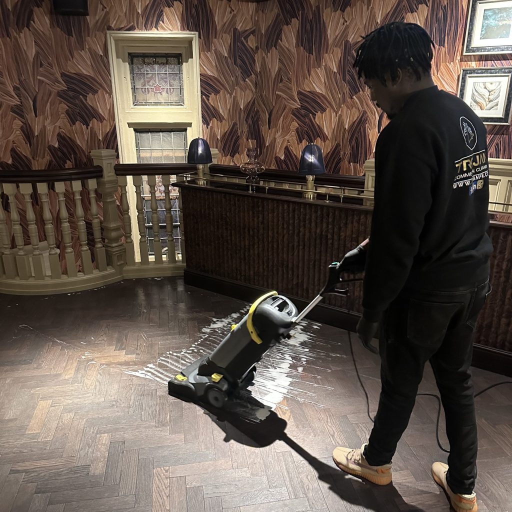 Trojan FM staff member cleaning the floor of a restaurant.