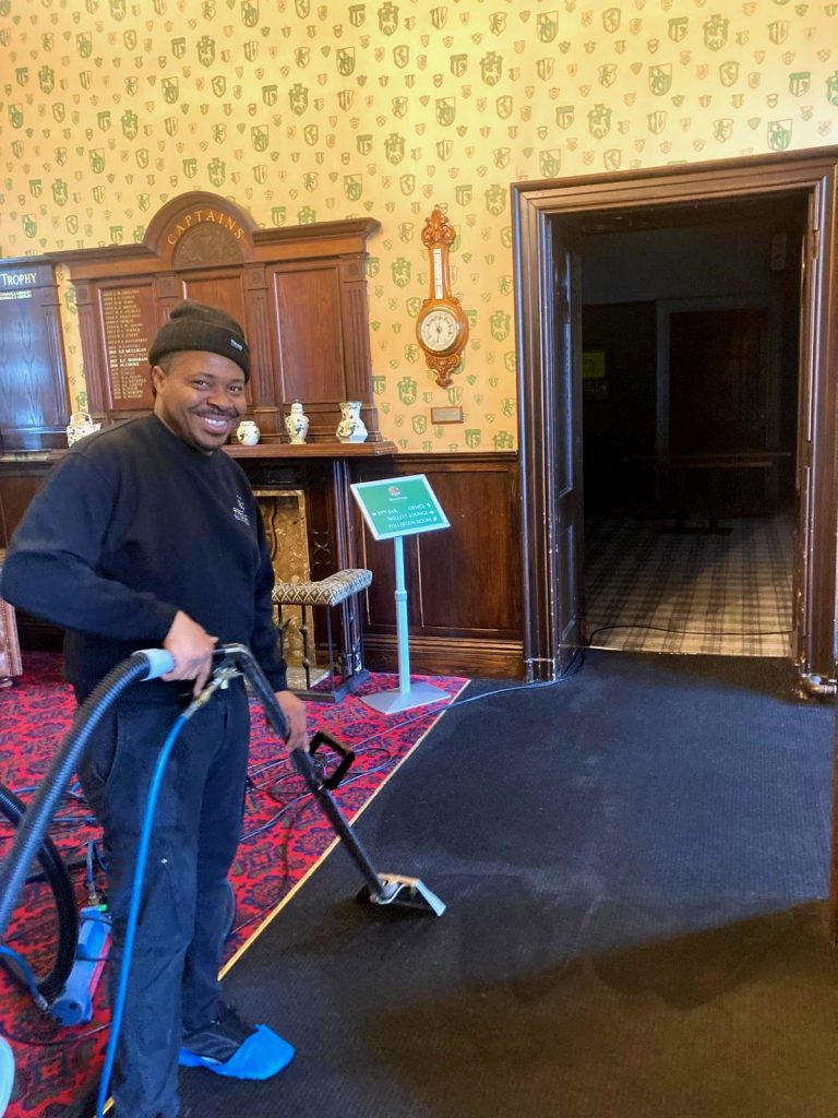 Trojan FM staff member cleaning a carpet, showing the difference before and after.